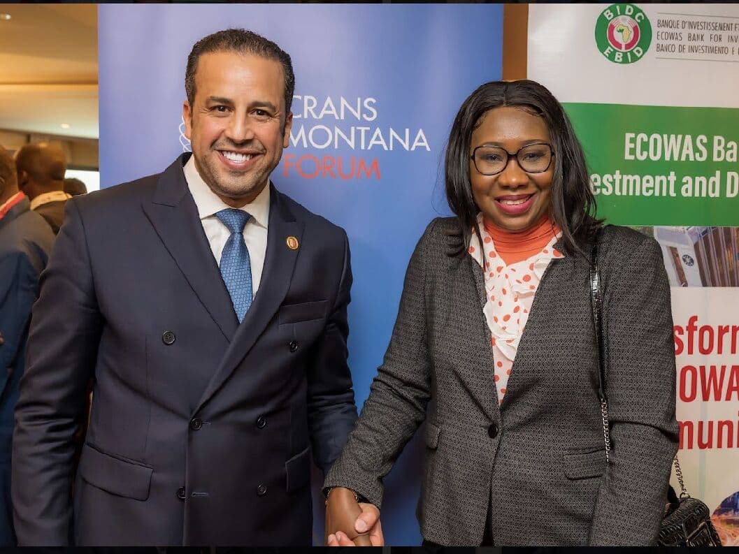 Kamal Benali with a delegate at the Crans Montana Forum, beside an ECOWAS Bank banner