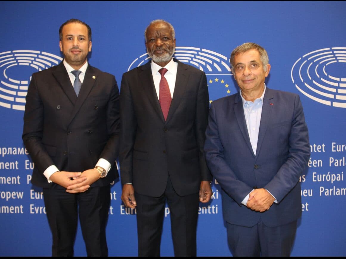 Kamal Benali with two delegates in front of the European Parliament backdrop